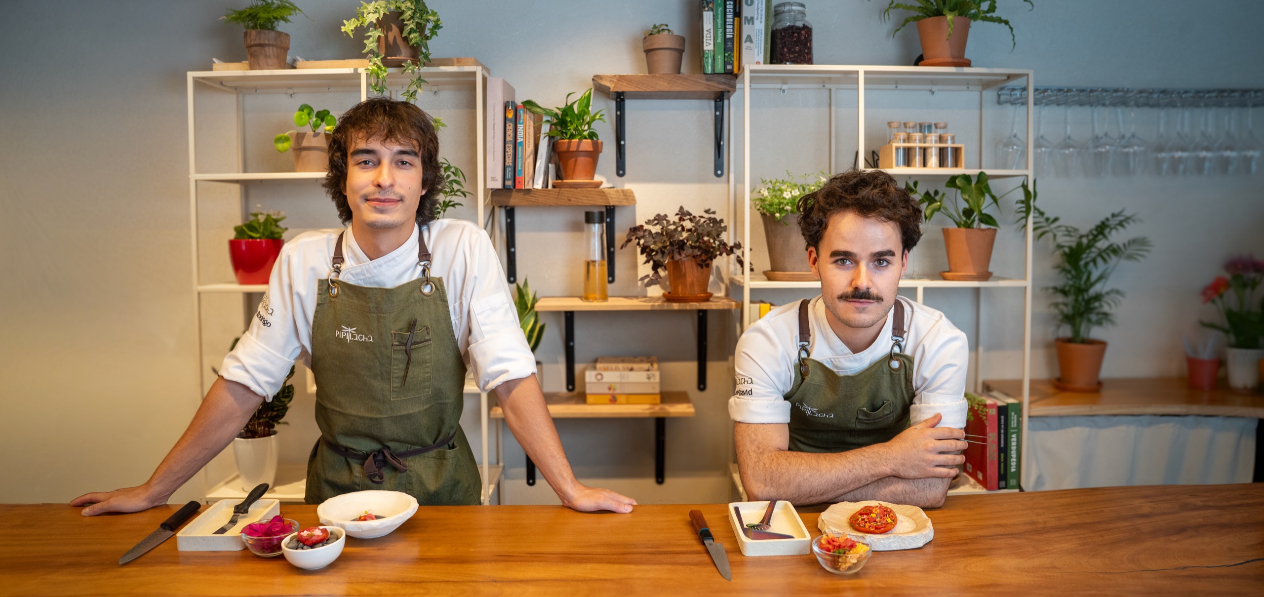 Arán and Noé behind the Pipilacha counter, flower courses plated in front