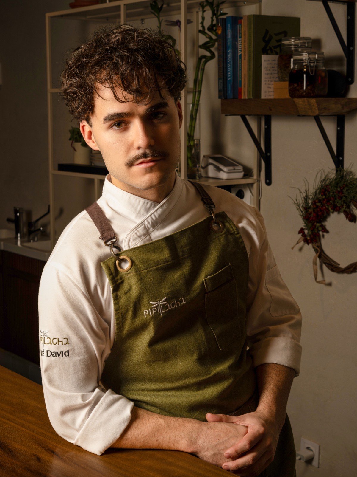 Noé David leaning on the counter, in the Pipilacha apron